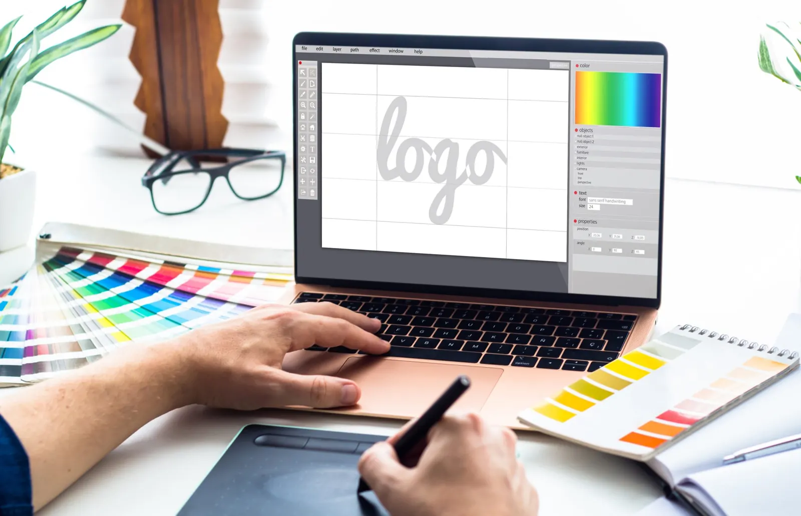 Grafik kreslí logo na tabletu u notebooku se vzorníkem barev